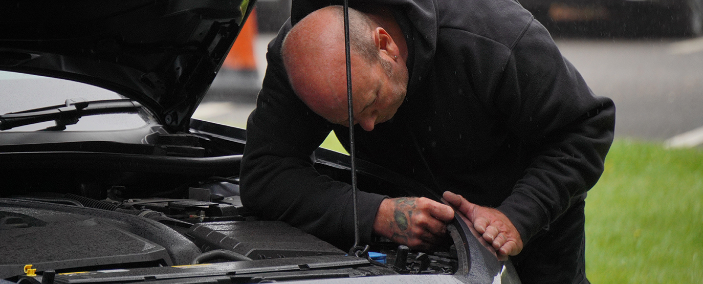 Certified technician working on panel of car with hood open