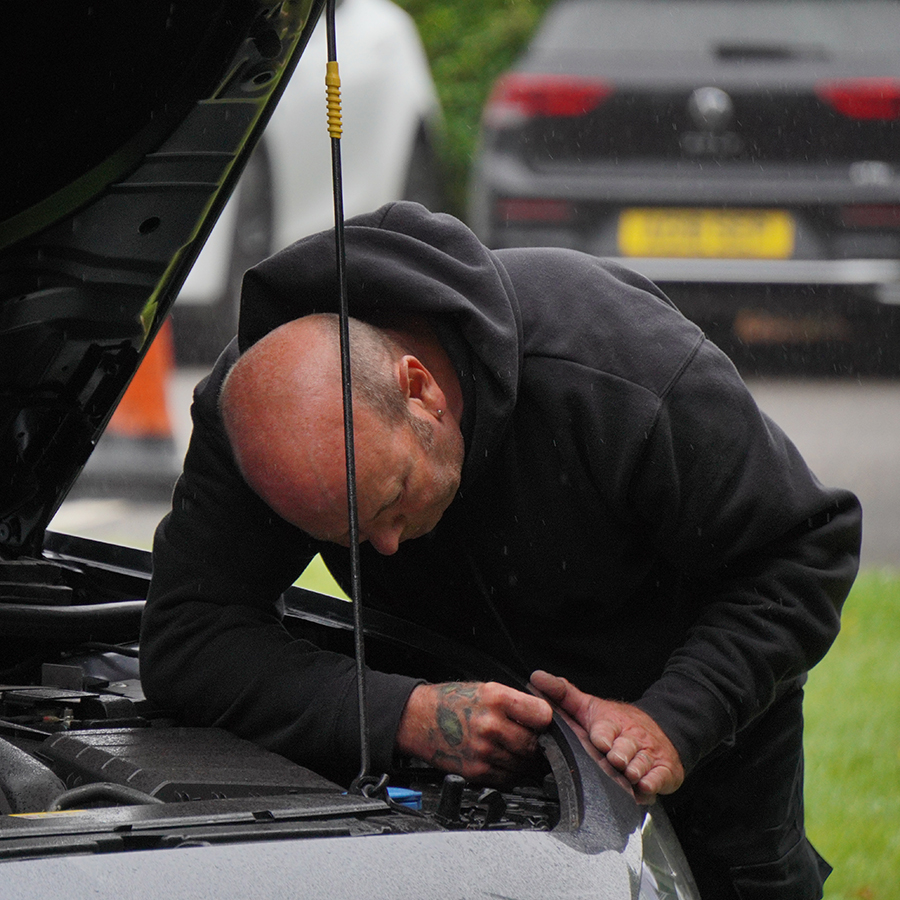 Certified technician working on panel of car with hood open