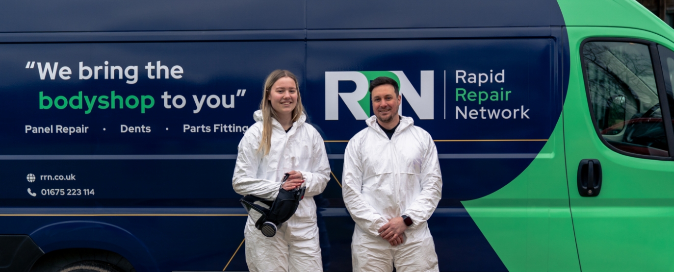 Two technicians smiling in front of van