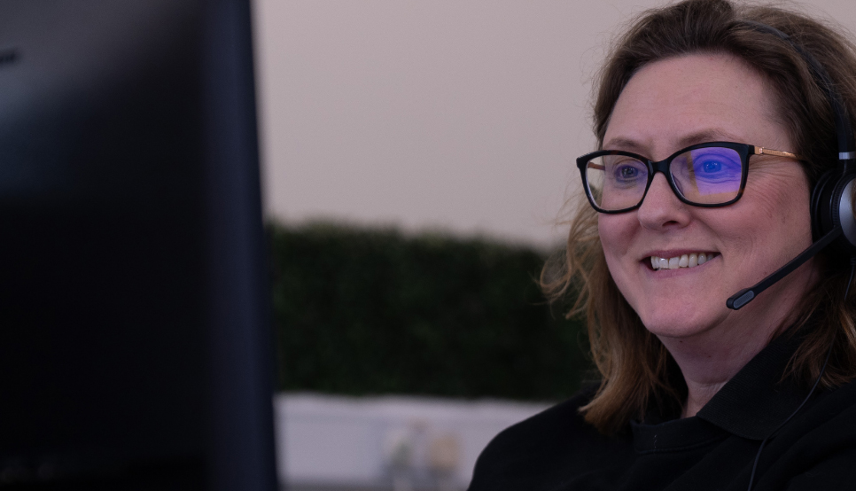 Customer support team member smiling whilst looking at computer screen